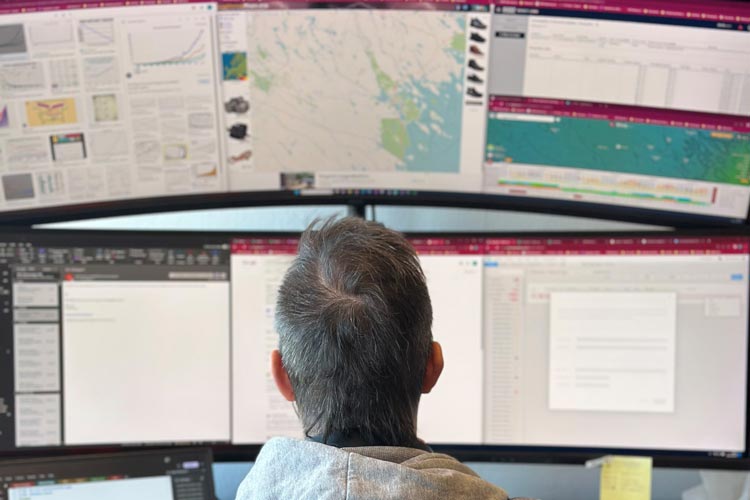 Man sitting in front of several computer screens