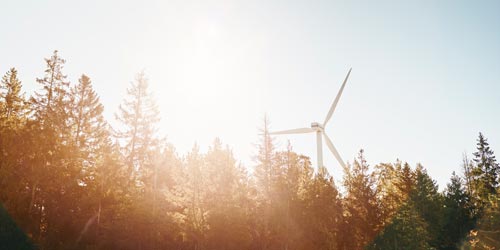 Silhouette of wind turbine behind trees